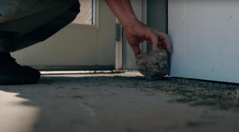 Hand placing a rock to prop open a school door